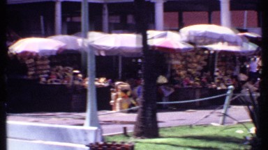 1969: crowds walk through a colorful market filled with produce. BAHAMAS