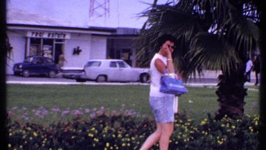 1969: a woman saying bye to someone on the road side,while waiting for someone