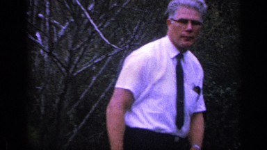 1968: man wearing a white shirt and glasses adjusting his tie