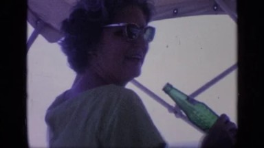 1968: Older Woman Drinking From Glass Bottle On Boat In Florida