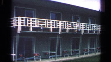 1968: a long apartment is located alone in front of garden and a guy watching