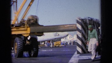 1963: two men dressed in green and white walk past a large machine, the camera