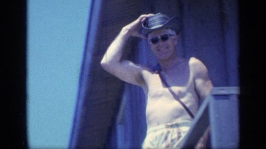 1968: a topless, middle-aged man wearing a cowboy hat walks down stairs FLORIDA