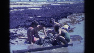 1968: a group of teens have fun building sand castles at the beach