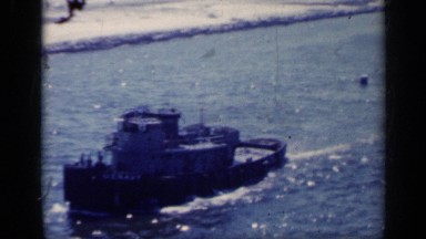 1962: large boat travelling on the water along a shore lined with rocks ITALY