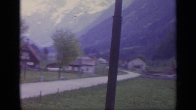 1962: a train driving by various buildings and people