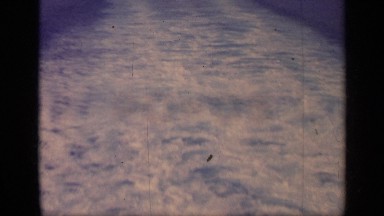 1962: foamy water extends for hundreds of feet behind a large ship as it glides