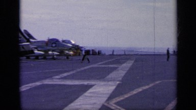 1962: us navy sailors and officers walk around the deck of an aircraft carrier