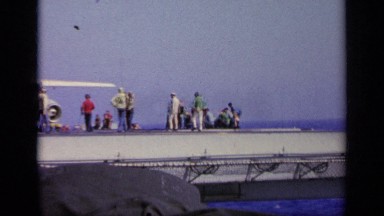 1963: view of aircraft carrier with crew out watching delivery of jet GREECE