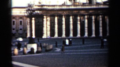 1962: building with cars driving past and people walking by a fountain CUBA