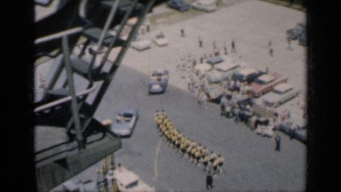 1962: an aerial view of a parking large concrete lot with people and vehicles in
