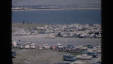 1962: cars parked by the beach while other cars are driving