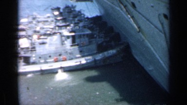1962: Five Tugboats Push Aircraft Carrier Near Dock in Cuba