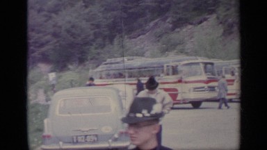 1962: Vehicles Parked Near Mountain with People Moving