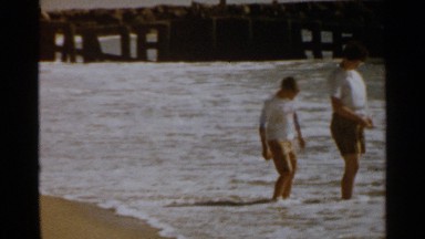 1959: brothers collect shells and play in waves at a beach. SAN FRANCISCO