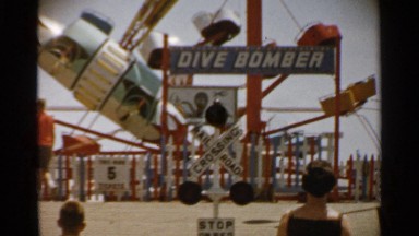 1959: a few people approach a dive bomber amusement ride which is motionless