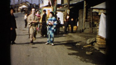 1952: Two Japanese Women in Traditional Costume Walk Down a Busy Street