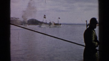 1952: a man watching the river and a boat with flag waving on the river air