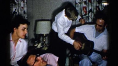 1952: Couple Sings Along to Guitar While Child Helps Man Strum, New Hampshire