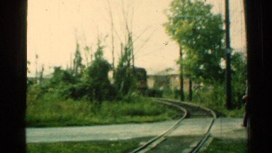 1953: a man walking across tracks as a single engine yellow train or trolley