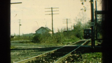 1953: retro footage of a train rolling through leaves at a steady pace.
