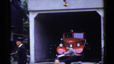 1953: a teenage people ride their bikes back and forth in front a garage. JAPAN