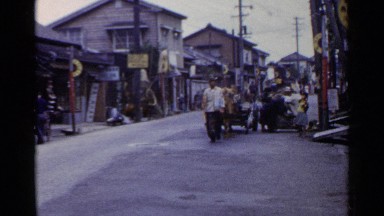 1953: an asian man leads an animal drawn wagon down a urban street JAPAN