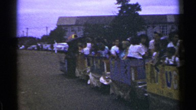 1953: a set of people sitting inside a train of cabin which is opened and moving
