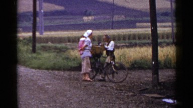 1953: mother and baby talk to farmer on a bike in rural setting. JAPAN