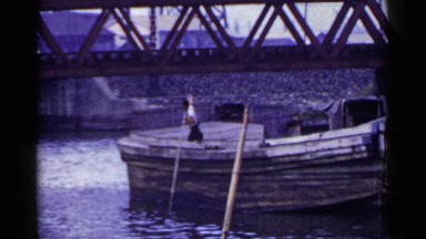 1953: chinese fisher man uses poles to dislodge his boat from the shallow water
