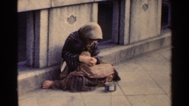 1953: a lady holding her child while sitting on the sidewalk JAPAN