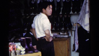1953: a boy is looking at the shoes in the shop, maybe he is looking to buy