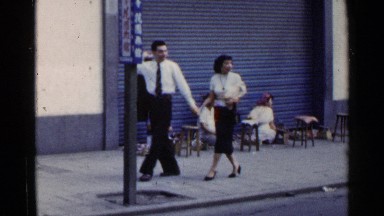1953: three street vendors sit on a street while people walk past. JAPAN