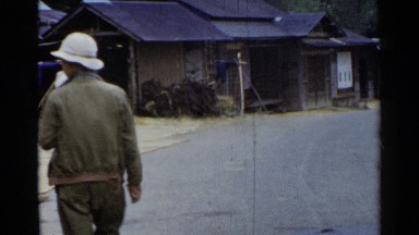 1953: man walks on side of road with buildings opposite group of females JAPAN