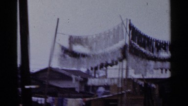 1953: a view of a lot of clothes drying in the sun behind a few businesses JAPAN
