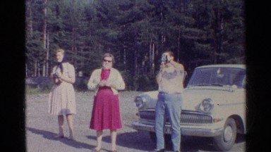 1961: happy family posing and taking photos in front of white car. GERMANY