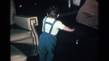 1963: A Baby Trying to Walk Using Sofa in His Home at Night Time Happily