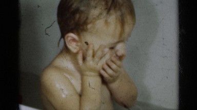1939: young child holds wet face with both hands while hair is being rinsed