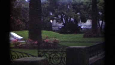 1949: Wrought Iron Gate Open to Marble Path of Dense Green Estate in New Orleans