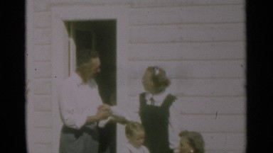 1949: family greeting each other outside of a house while two children walk