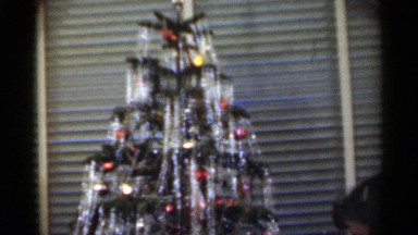 1949: girl presenting a doll under christmas tree, enjoying a happy moment.