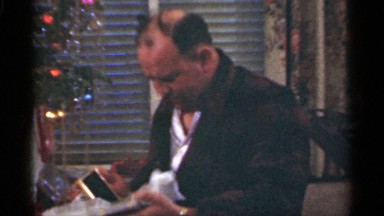 1949: man opening present of a picture frame at christmas. SANTA CRUZ CALIFORNIA