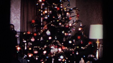 1959: a christmas tree beautifully decorated with lights, bells, paper and gifts