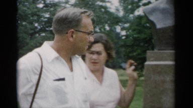 1956: husband and wife mingles in a crowd and look at a statue. JONES BEACH