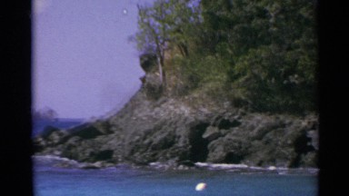 1967: ocean and rocks with ship in the distance, camera panning left to right US