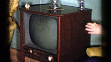 1955: glamorous middle aged woman sitting next to tv set while talking NEW YORK