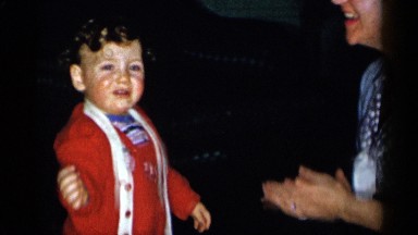 1955: toddler dancing and smiling while middle aged woman claps and laughs