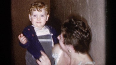 1955: a woman who is holding a small child and trying to get him to wave