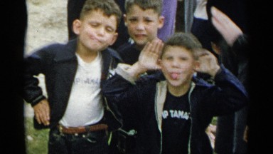 1954: three young boys stand in front of a crowd of people and make faces