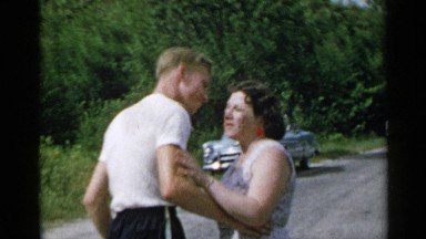 1954: a young man kisses an older lady and walks away as he waves to her